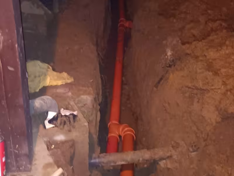 Detail ukladania oranžového potrubia pre odpadovú kanalizáciu do zeme.